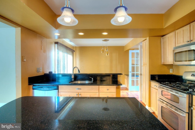 kitchen with pendant lighting, dark stone countertops, sink, and stainless steel appliances