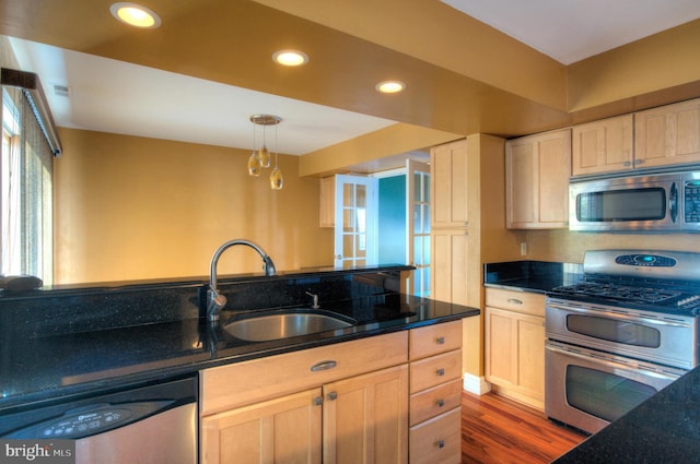 kitchen with sink, light brown cabinets, pendant lighting, appliances with stainless steel finishes, and hardwood / wood-style flooring