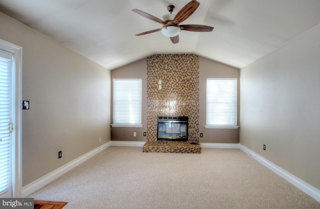 unfurnished living room with carpet flooring, plenty of natural light, a large fireplace, and vaulted ceiling