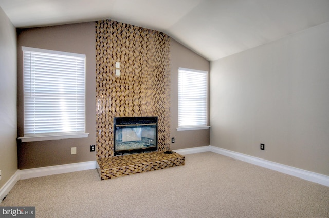 living room with a tile fireplace, carpet floors, a healthy amount of sunlight, and lofted ceiling