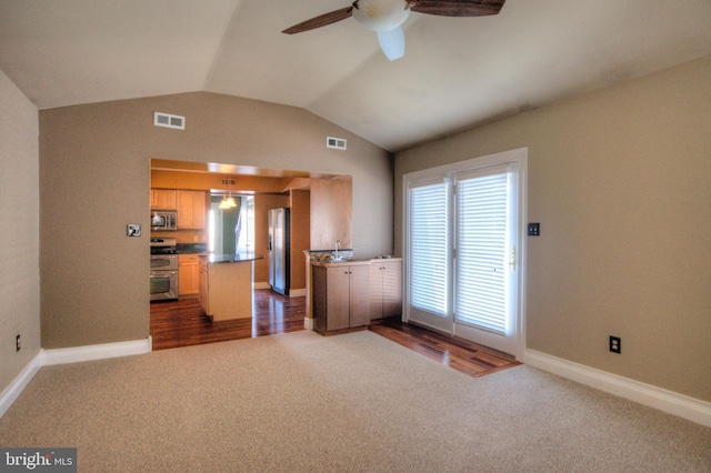 kitchen with dark colored carpet, appliances with stainless steel finishes, a kitchen island, and ceiling fan