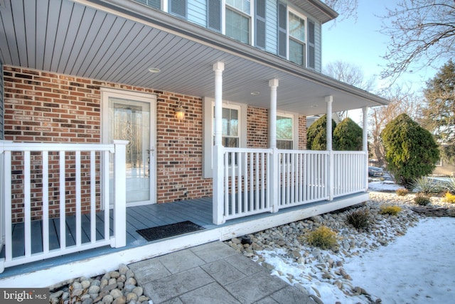 snow covered property entrance with covered porch