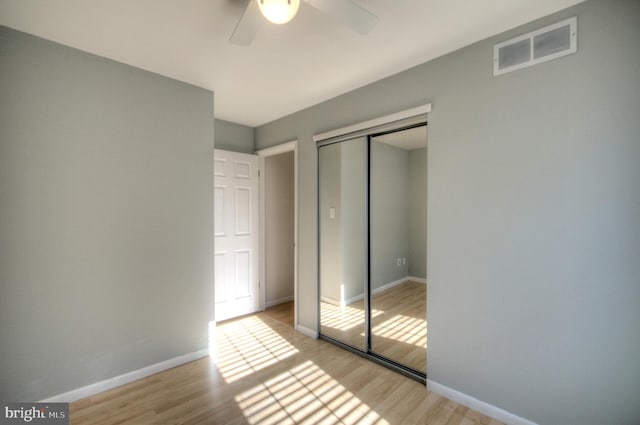 unfurnished bedroom featuring ceiling fan, light hardwood / wood-style floors, and a closet