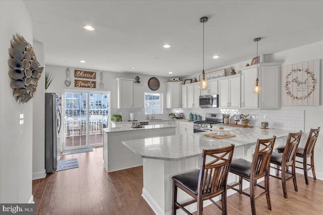 kitchen featuring white cabinets, appliances with stainless steel finishes, decorative light fixtures, and sink