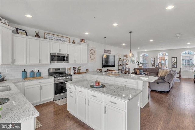 kitchen with white cabinets, pendant lighting, a center island, and stainless steel appliances