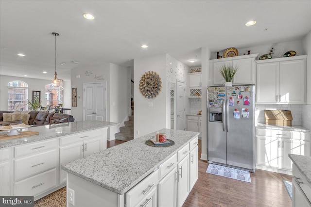 kitchen with decorative backsplash, stainless steel fridge, decorative light fixtures, a center island, and white cabinetry