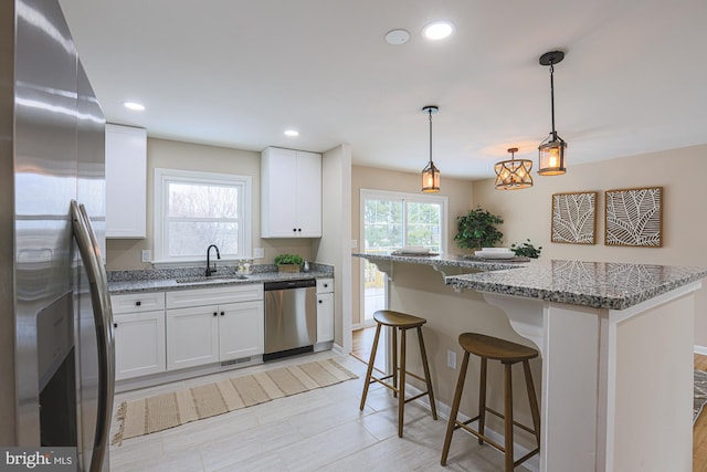 kitchen with stone counters, sink, white cabinets, and appliances with stainless steel finishes