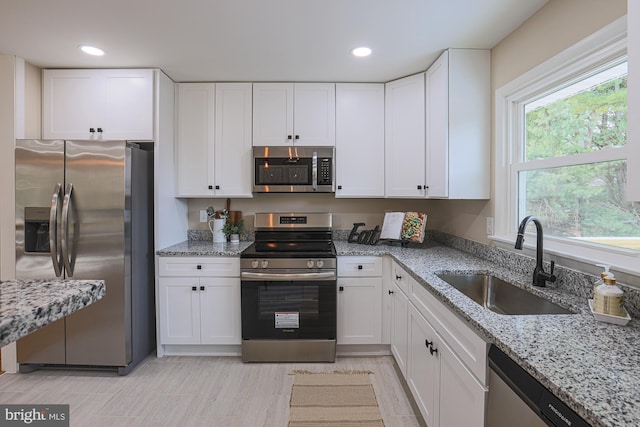 kitchen with light stone counters, white cabinetry, sink, and appliances with stainless steel finishes