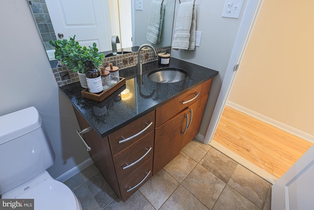 bathroom with decorative backsplash, vanity, and toilet