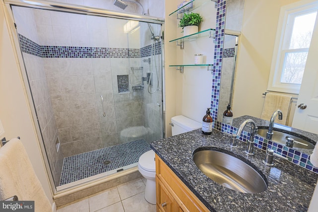 bathroom featuring tile patterned floors, vanity, a shower with shower door, and toilet