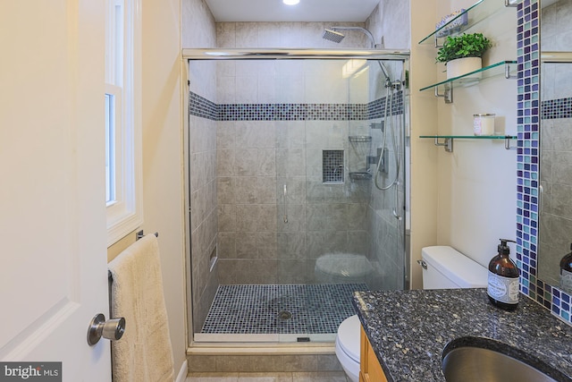 bathroom with vanity, toilet, and a shower with door