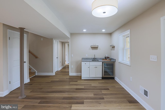 bar featuring white cabinetry, sink, light stone countertops, wine cooler, and dark hardwood / wood-style floors