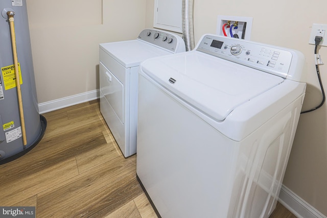 clothes washing area with washing machine and clothes dryer, hardwood / wood-style floors, and water heater