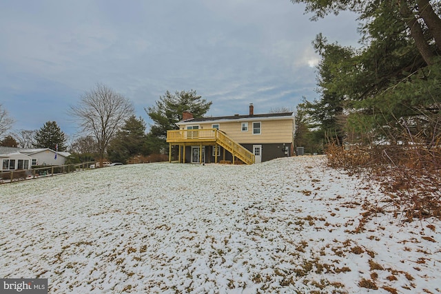 snow covered house featuring a wooden deck