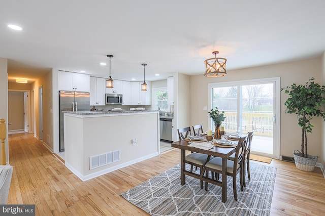 dining room featuring a chandelier, a healthy amount of sunlight, and light hardwood / wood-style floors