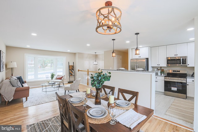 dining space with light hardwood / wood-style floors and an inviting chandelier