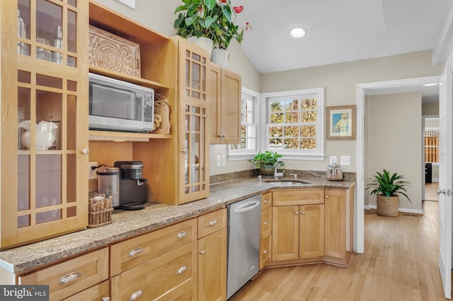 kitchen with lofted ceiling, sink, appliances with stainless steel finishes, light stone countertops, and light hardwood / wood-style floors