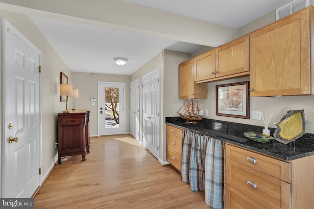 kitchen featuring light hardwood / wood-style flooring, dark stone counters, and light brown cabinets