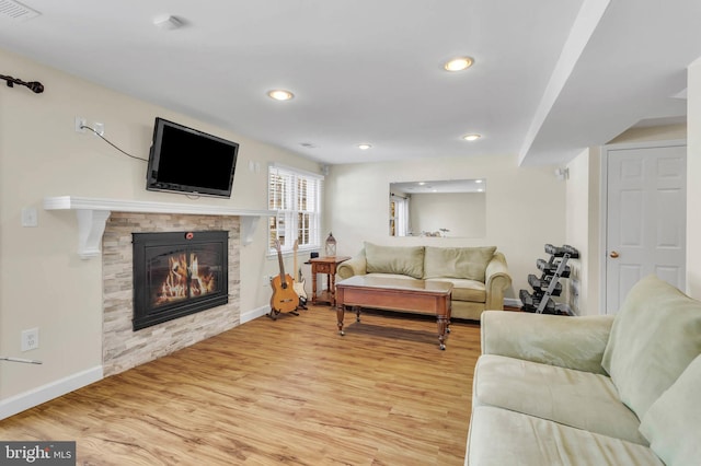 living room featuring a stone fireplace and light wood-type flooring