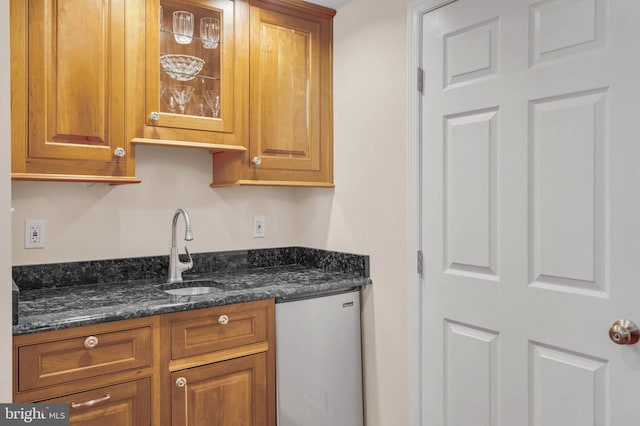 kitchen with dishwasher, sink, and dark stone counters