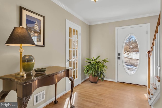 entryway with ornamental molding and light hardwood / wood-style floors