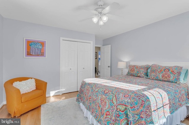 bedroom with light wood-type flooring, ceiling fan, and a closet