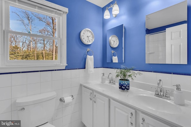 bathroom with vanity, toilet, tile walls, and a shower