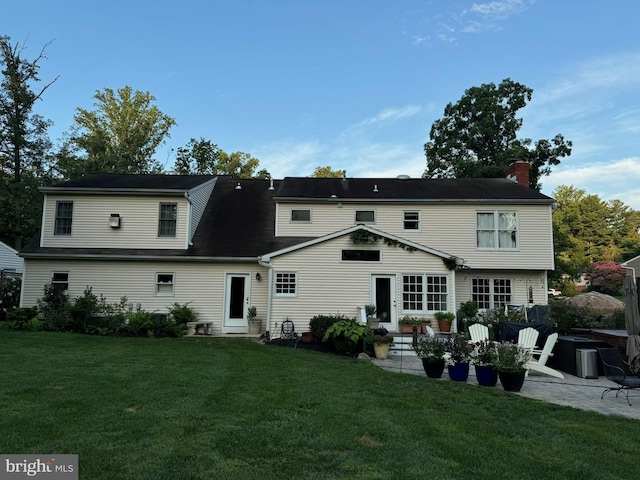 back of property featuring a patio area and a lawn