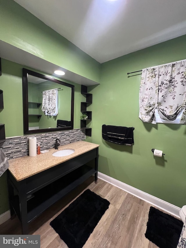 bathroom with hardwood / wood-style flooring, vanity, and backsplash