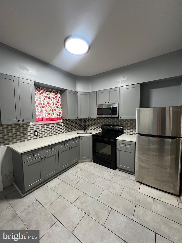 kitchen featuring decorative backsplash, appliances with stainless steel finishes, gray cabinets, and light tile patterned floors