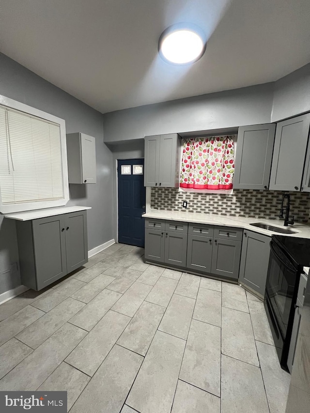 kitchen featuring gray cabinetry, backsplash, sink, and black range with electric cooktop