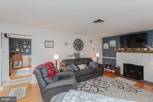 living room featuring light hardwood / wood-style floors and a brick fireplace