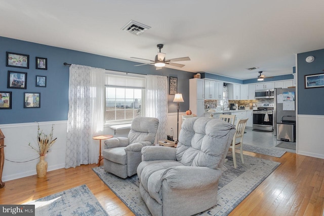 living room featuring ceiling fan, sink, and light hardwood / wood-style floors