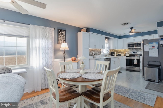 dining area featuring ceiling fan, plenty of natural light, sink, and light wood-type flooring