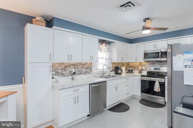 kitchen featuring white cabinetry, sink, ceiling fan, light stone countertops, and appliances with stainless steel finishes