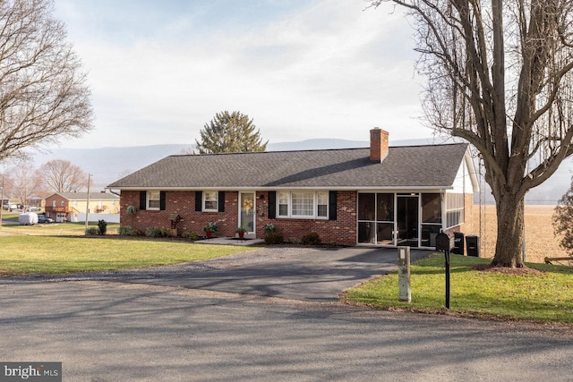 single story home featuring a sunroom and a front yard