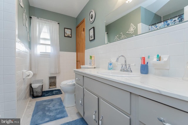 bathroom with tile patterned floors, vanity, toilet, and tile walls