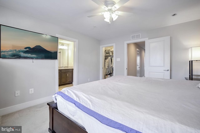 carpeted bedroom featuring ceiling fan, a spacious closet, ensuite bathroom, and a closet