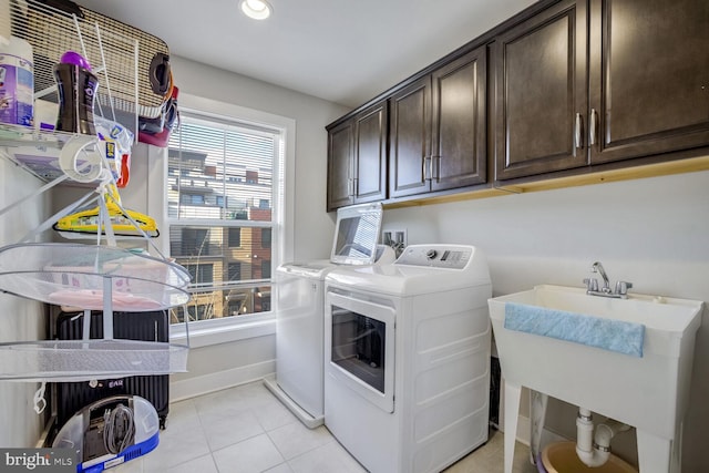 laundry room featuring washing machine and clothes dryer, sink, light tile patterned floors, and cabinets