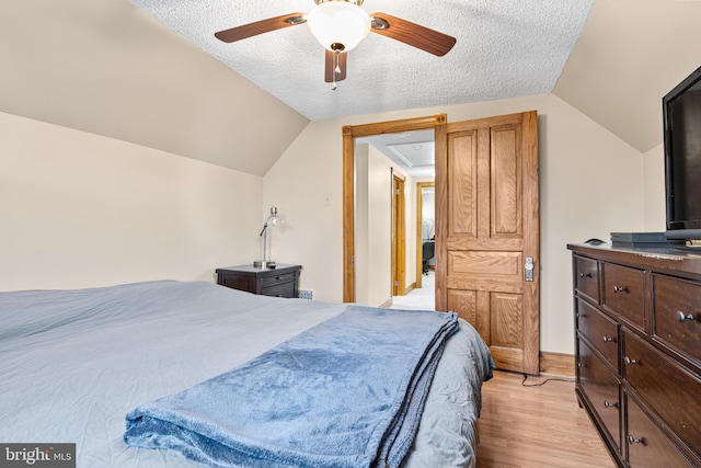 bedroom with light wood-type flooring, a textured ceiling, ceiling fan, and lofted ceiling