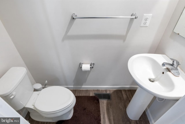 bathroom with hardwood / wood-style flooring, toilet, and sink