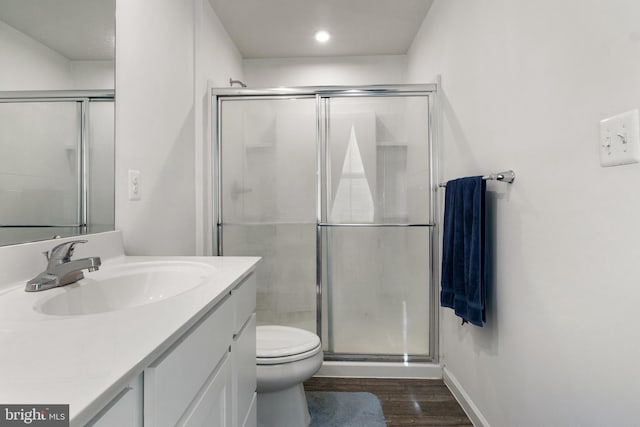 bathroom with vanity, wood-type flooring, a shower with shower door, and toilet