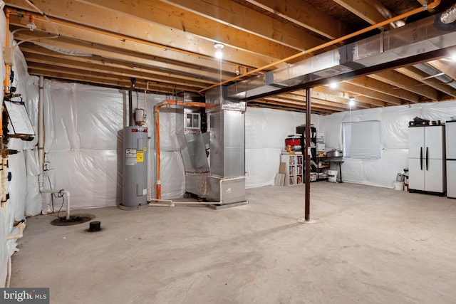 basement with heating unit, white fridge, and water heater