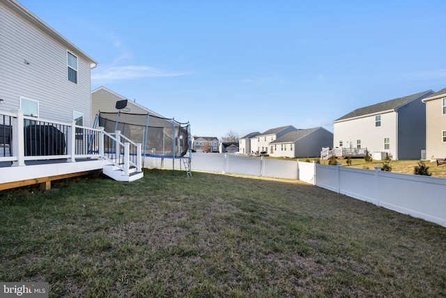 view of yard featuring a trampoline and a wooden deck