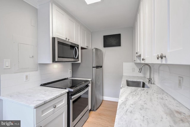 kitchen featuring white cabinetry, sink, light stone countertops, light hardwood / wood-style flooring, and appliances with stainless steel finishes