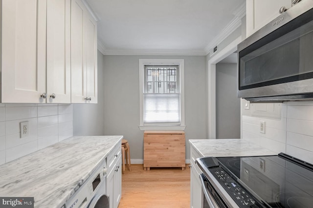 kitchen with light stone countertops, stainless steel appliances, white cabinets, washer / dryer, and light hardwood / wood-style floors