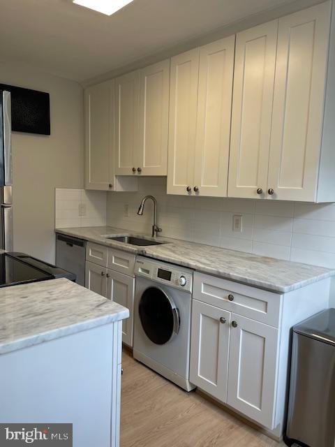 washroom featuring washer / clothes dryer, sink, and light hardwood / wood-style floors