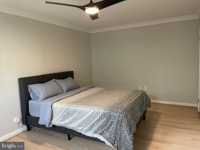 bedroom featuring ceiling fan, light hardwood / wood-style floors, and crown molding