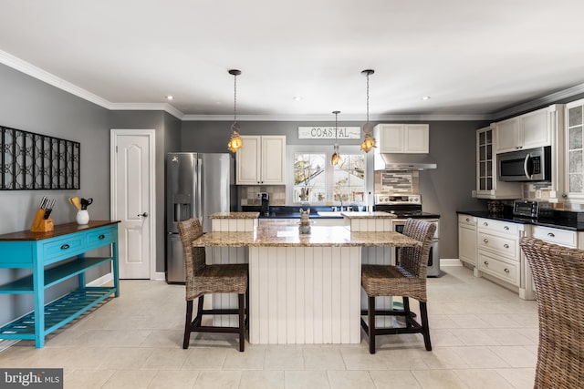 kitchen featuring a breakfast bar area, dark stone countertops, a kitchen island, stainless steel appliances, and extractor fan