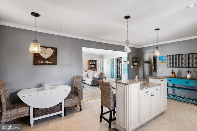 kitchen with light stone counters, white cabinets, decorative light fixtures, and a kitchen island